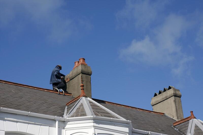 man on the roof beside the chimney